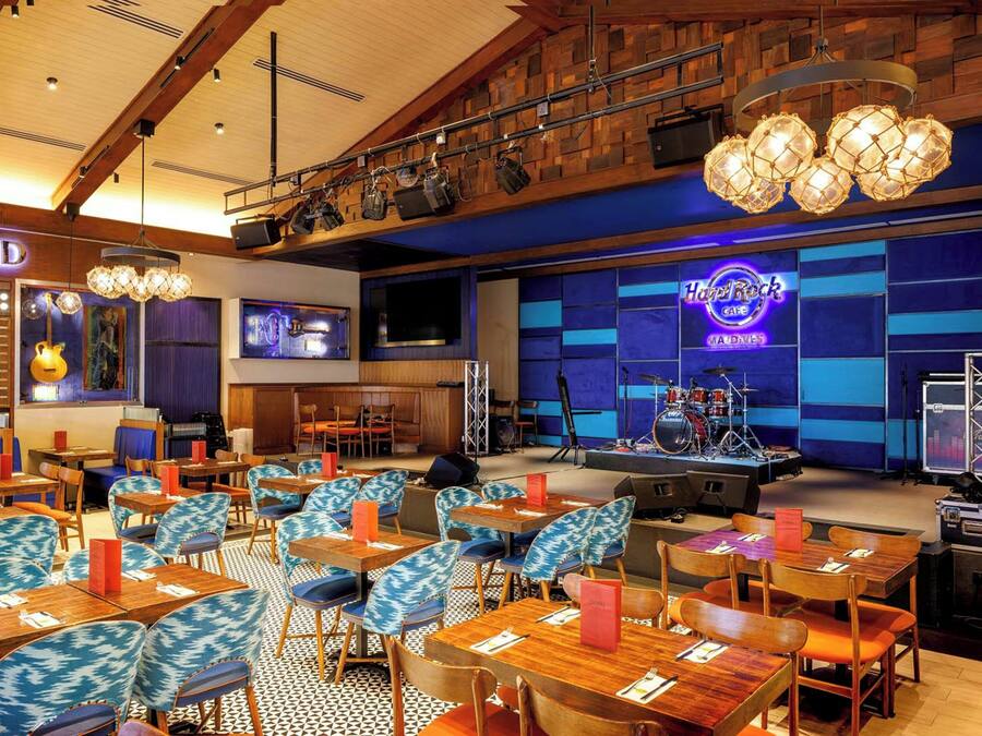 A restaurant with a stage, tables, chairs, and a neon sign.