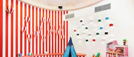 Une salle de jeux avec un mur à rayures, une tente et une maison de poupées.