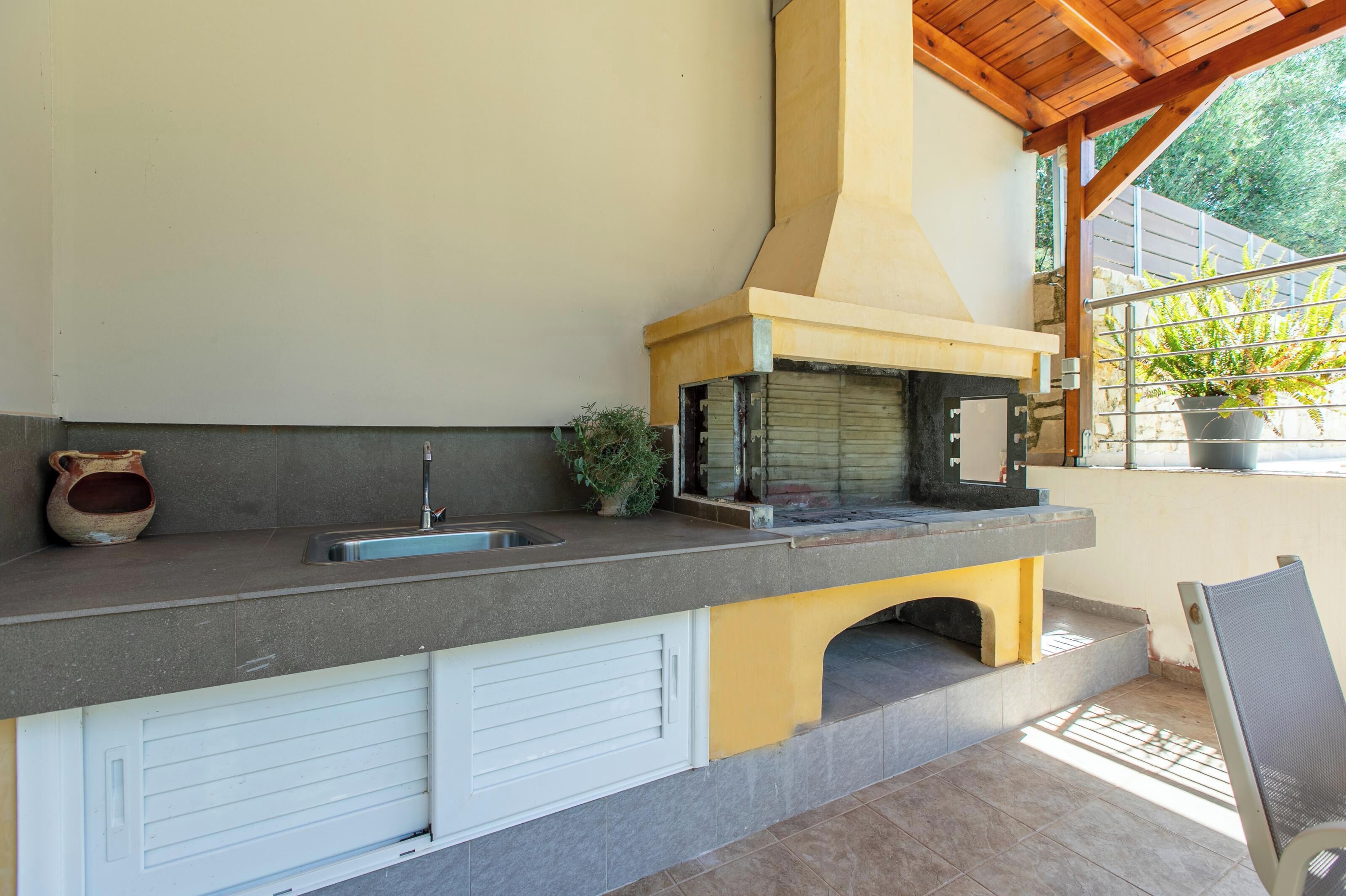 An outdoor kitchen with a sink, a potted plant, and a grill.