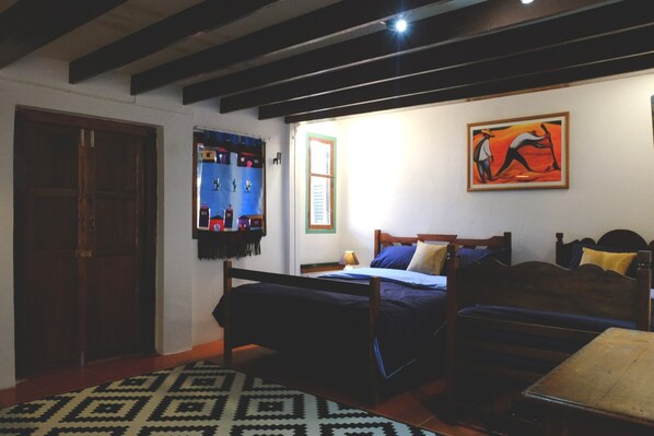 Una habitación con cama, banco, mesa y puerta.