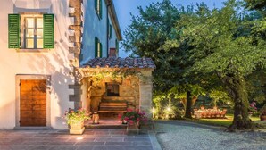 A stone archway leading to a building with a tiled roof and a wooden door. - Verdidea - PALAZZO DELLE ROSE (Monterchi)