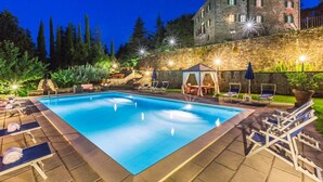 A rectangular swimming pool with lounge chairs and umbrellas, surrounded by a stone wall and vegetation. - Verdidea - PALAZZO DELLE ROSE (Monterchi)