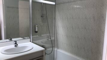 Une salle de bain moderne avec un lavabo blanc, un miroir et une douche à parois de verre.