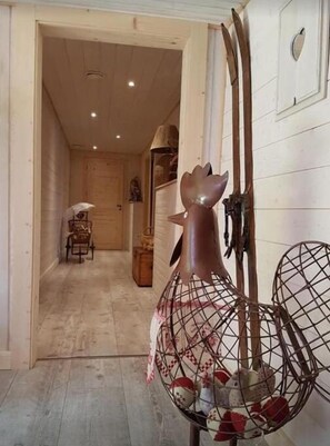 A room with a wooden floor, a chair, a table with a decorative item, and a wall-mounted shelf. - La Ferme de Là-haut B&B (Haut-du-Them-Château-Lambert)