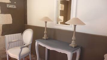 Un baño con una silla blanca, un tocador con espejo y dos lámparas de pared.