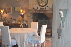 Un comedor con una mesa redonda, sillas blancas, un reloj y una chimenea.