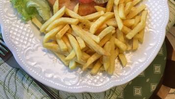 Un plato de comida con milanesa, papas fritas, lechuga y guarniciones.