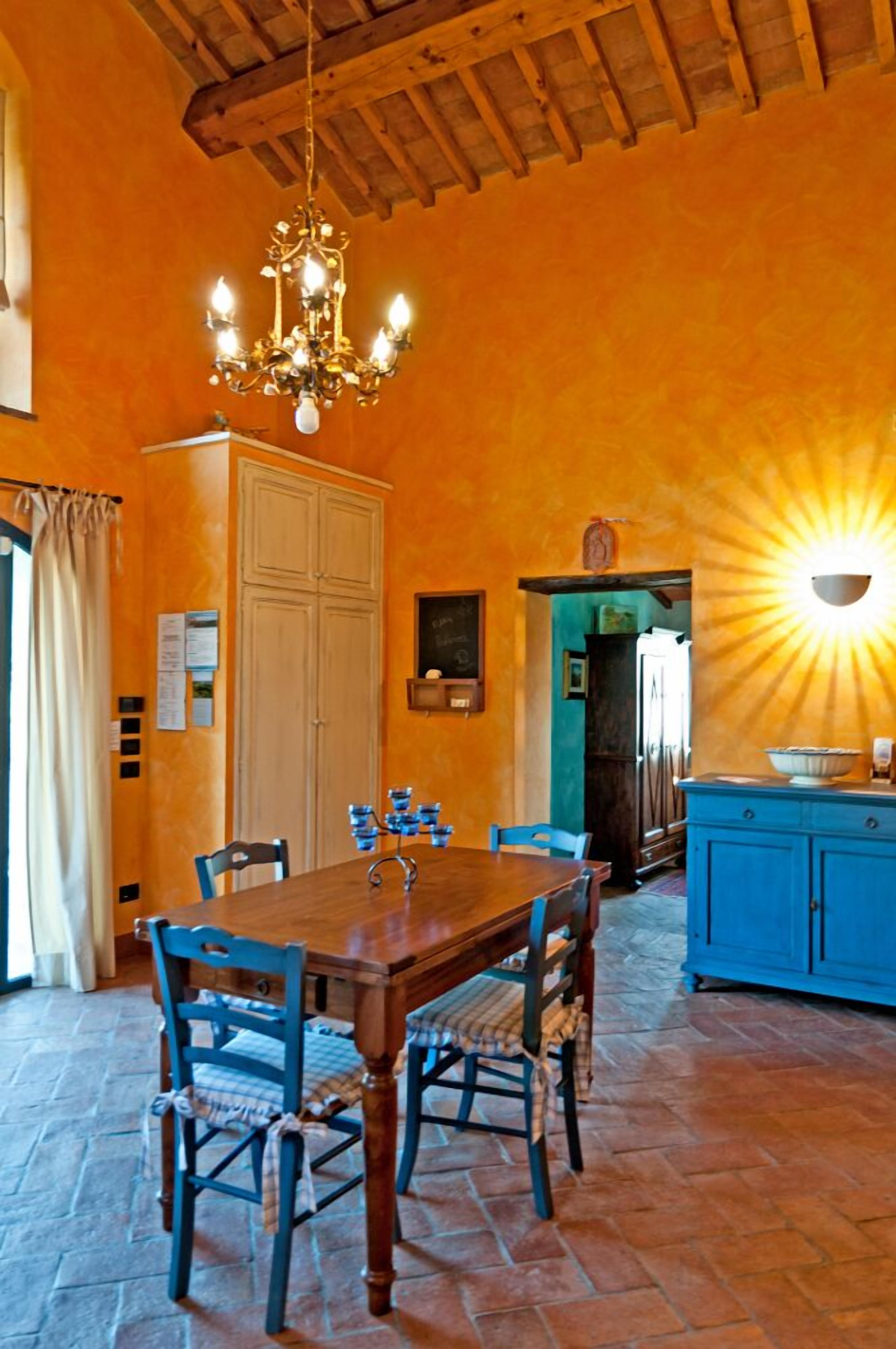 Ein Essbereich mit Holztisch und -stühlen, einer Chandelüster und einem blauen Schrank.