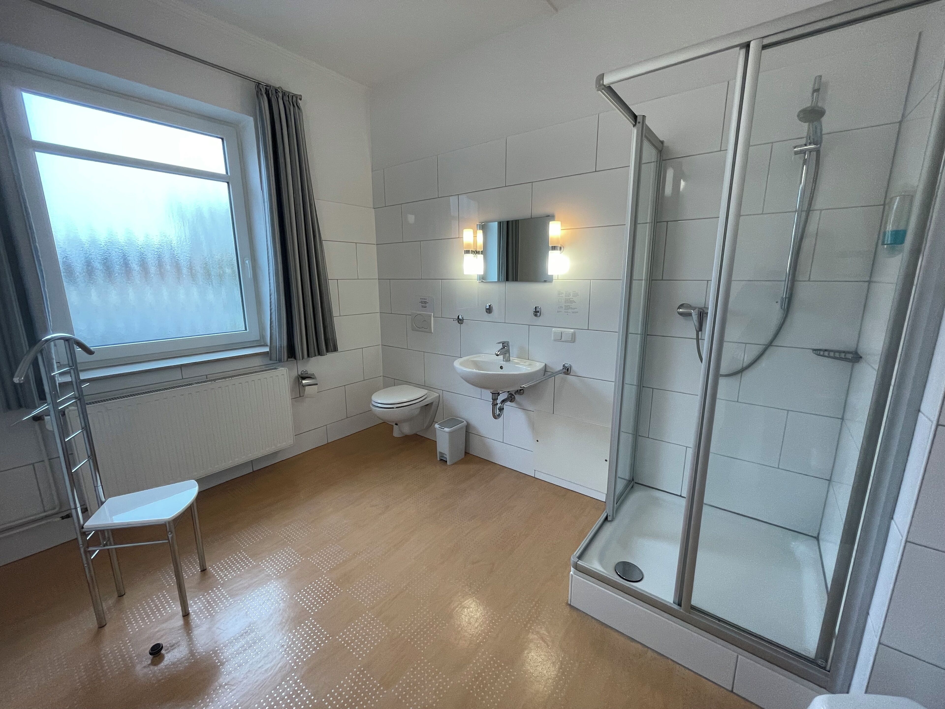 Un baño moderno con inodoro, lavamanos y cabina de ducha de vidrio.