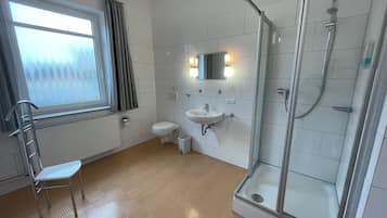 Et moderne badeværelse med toilet, vask og brusekabine i glas.