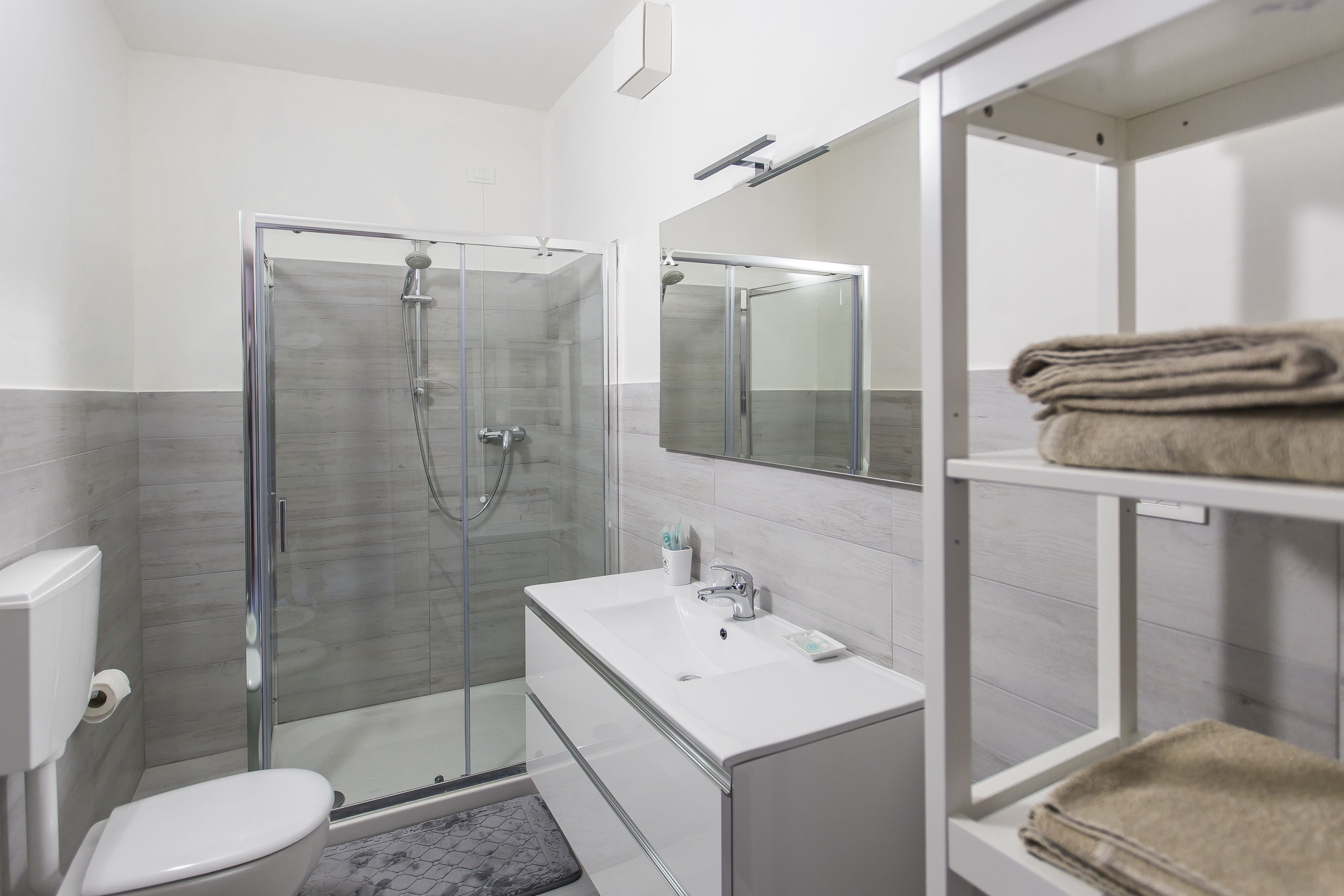 Ein modernes Badezimmer mit einer Duschkabine, einem weißen Waschbecken und einer Toilette.