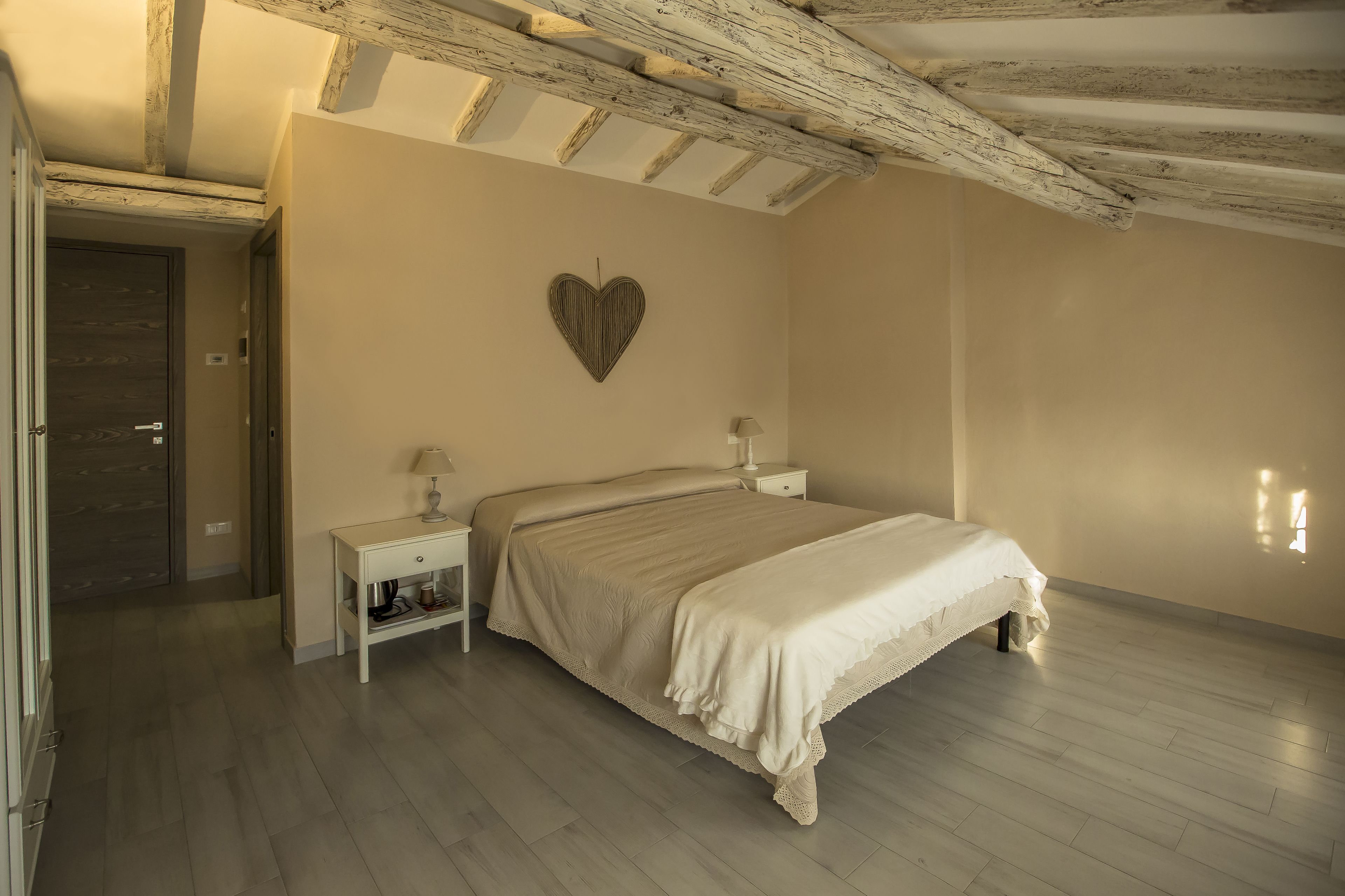 Un dormitorio con cama, mesitas de noche, un adorno en forma de corazón en la pared y techo de madera.