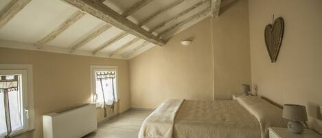Une chambre à coucher avec un lit, une table de chevet, une lampe, un radiateur et un objet décoratif en forme de cœur accroché au mur.
