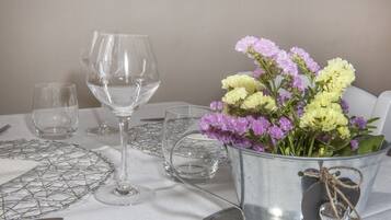 Ein Tisch, gedeckt mit klarem Glasgeschirr, einem Metallkübel mit Blumen und einer Drahtgitter-Tischmatte.