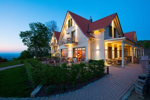 A two-story house with a red-tiled roof, a balcony, and a patio area with outdoor furniture.