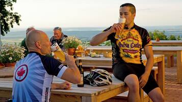 Two people sitting at a wooden table outdoors with a scenic view in the background.