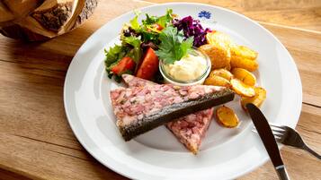 A plate of food with a slice of meat, potatoes, salad, and a small container of sauce.