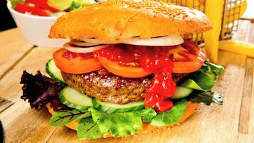 A hamburger with lettuce, tomato, and a bun on a wooden surface.