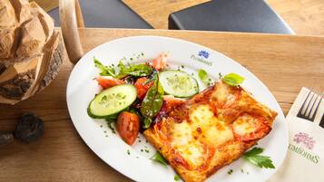 Ein Teller Essen mit Salat und einer Pizza auf einem Holztisch.