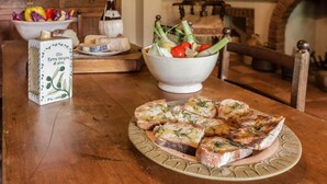 A wooden table with a plate of garlic bread, a bowl of salad, and a box of extra virgin olive oil. - Verdidea - VILLA RONCOSI (Monsummano Terme)