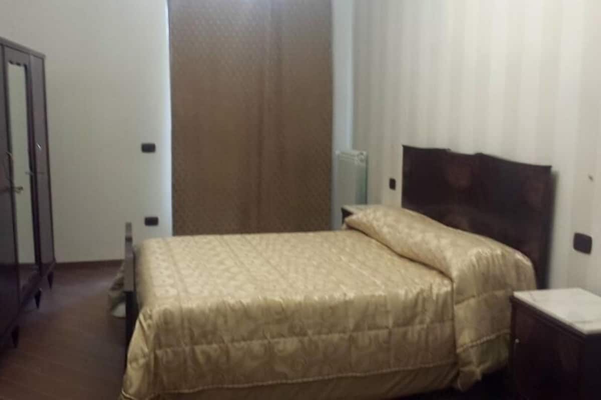 A bedroom with a bed, a wardrobe, and a bedside table.
