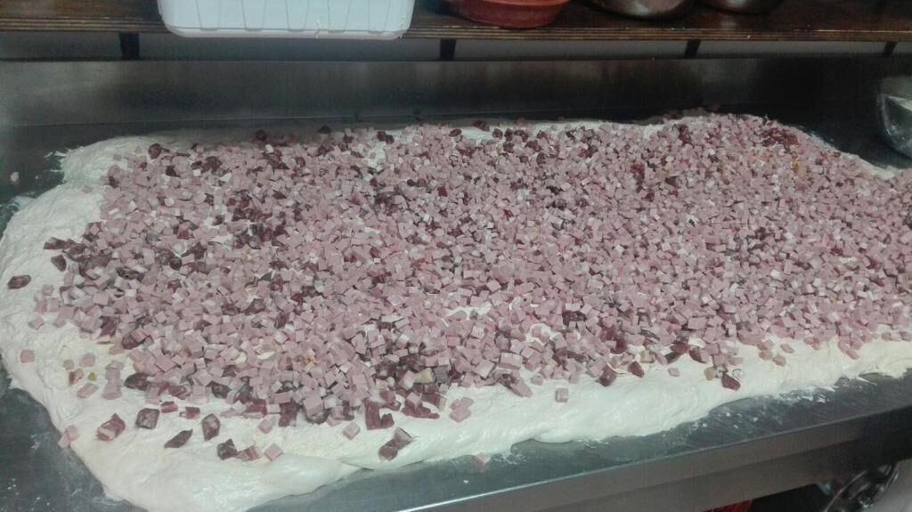Een platbrood met in blokjes gesneden vlees op een metalen oppervlak.