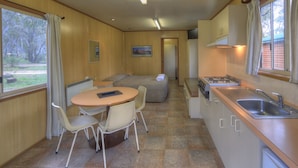 Una cocina compacta con comedor, un pequeño espacio de asientos y una ventana con cortinas.