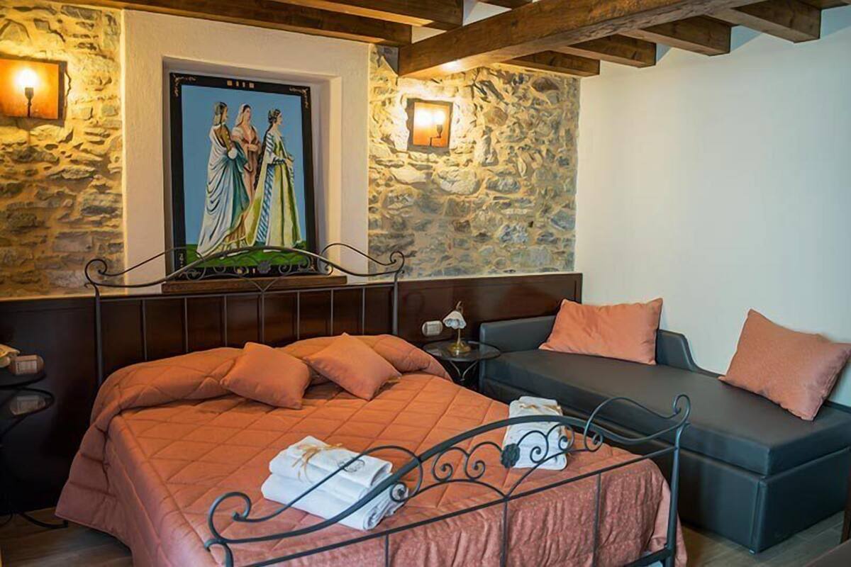Quarto com cama, sofá e um quadro na parede.