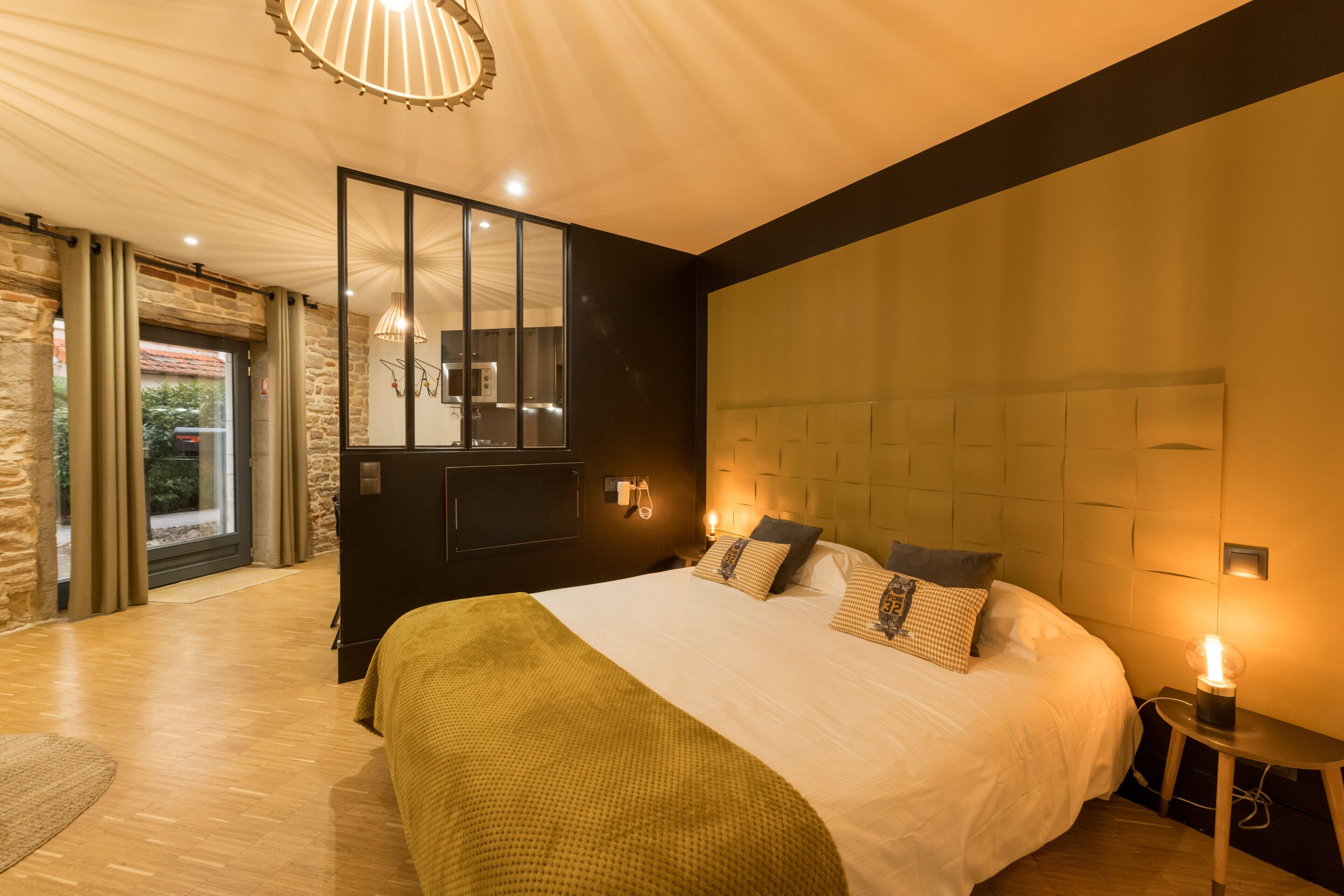 Ein modernes Schlafzimmer mit einem großen Bett, einem Spiegel und Blick ins Freie.
