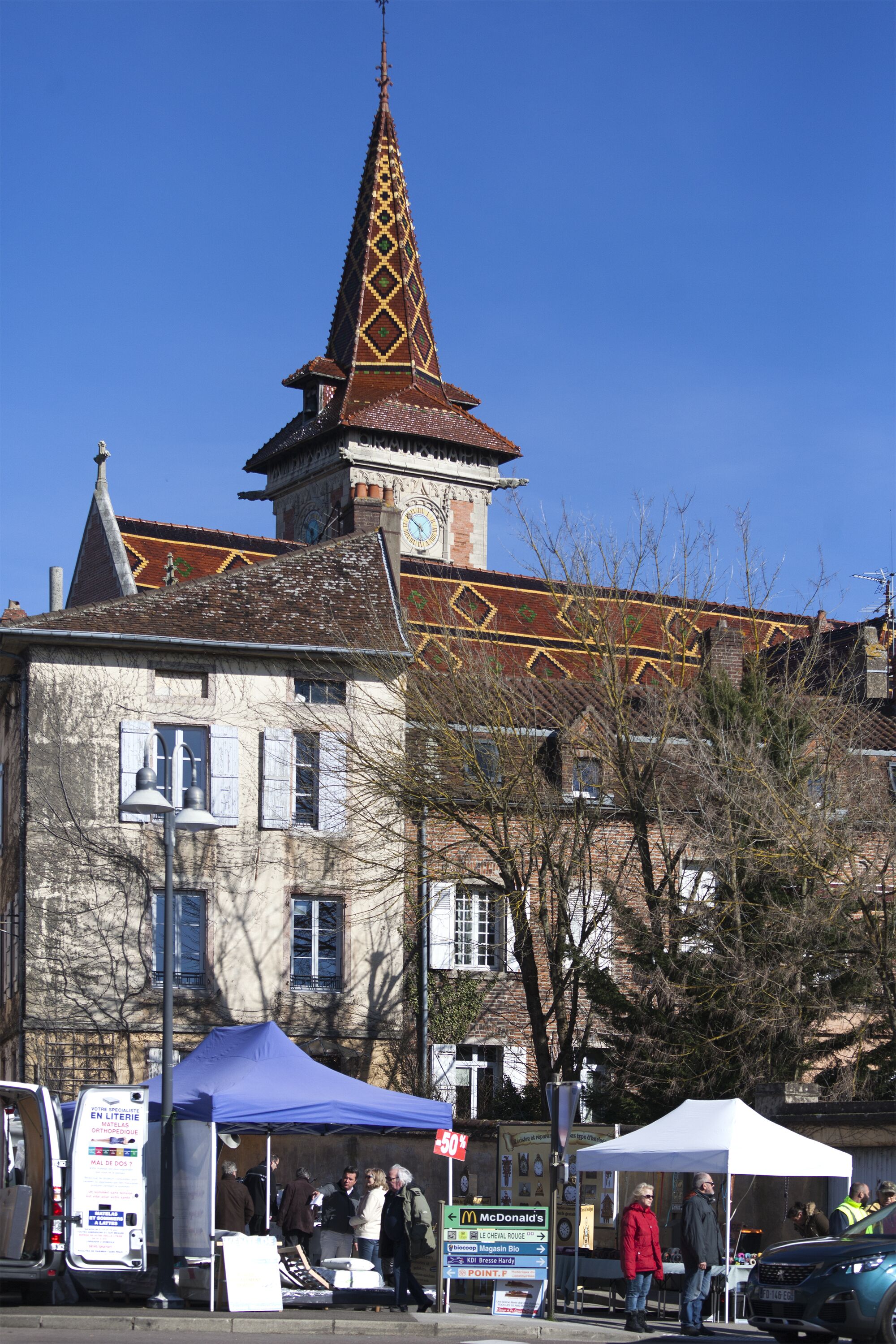 A historic building with a clock tower, a blue tent, and a McDonald's sign.