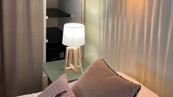 Ein Hotelzimmer mit einem Bett, einer Nachttischlampe, einem kleinen Tisch mit Lampe sowie einer Wandleuchte.