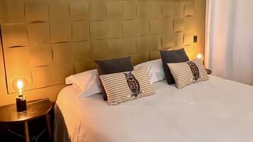 A hotel room with a tufted headboard, a neatly made bed with white linens, and two bedside lamps.