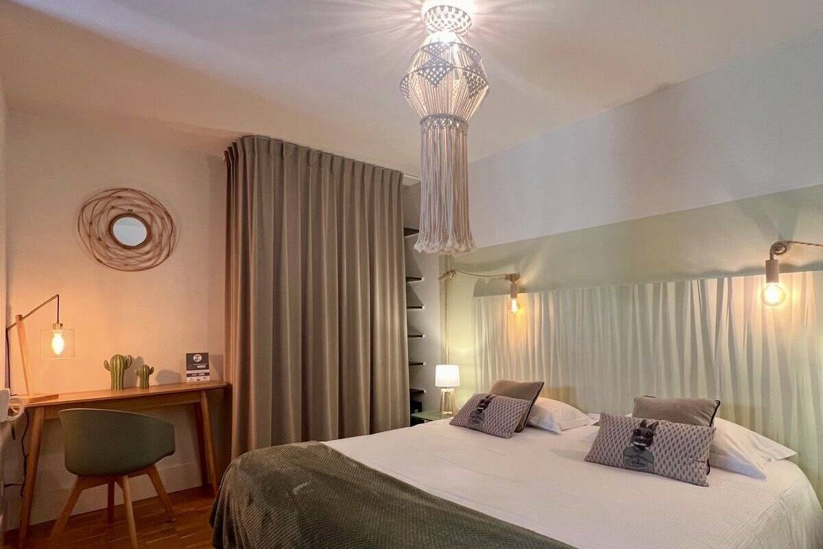 A hotel room with a large bed, a desk with a chair, a lamp, and a decorative ceiling light.