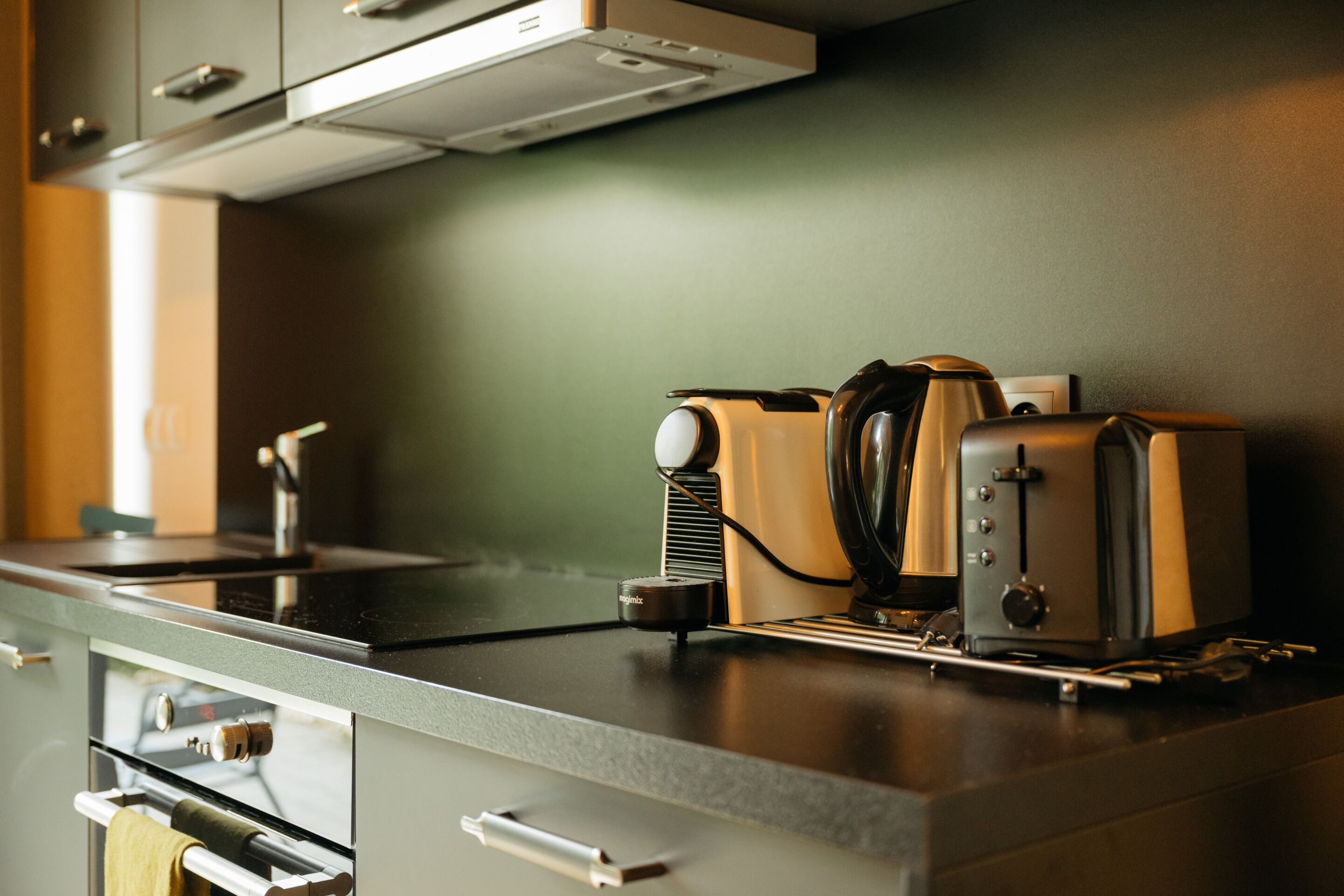 A kitchen with a modern design, featuring a stainless steel countertop, a built-in oven, and a range hood.
