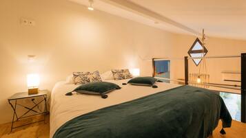 Ein Schlafzimmer mit einem großen Bett, zwei Nachttischen und Blick ins Freie.