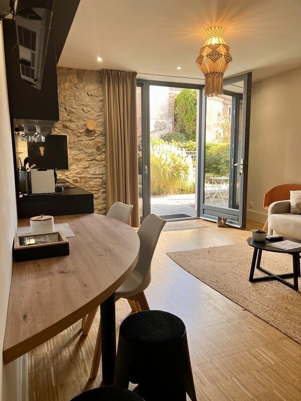Una cocina moderna con una pared de piedra, una zona de comedor con una mesa redonda y sillas, y una sala de estar con un sofá y una mesa de centro.