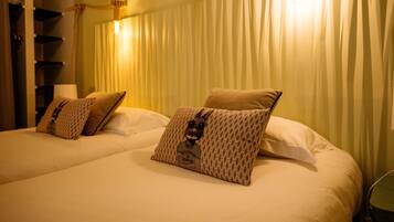 A hotel room with two beds, each with a patterned pillow and a lamp on the nightstand.