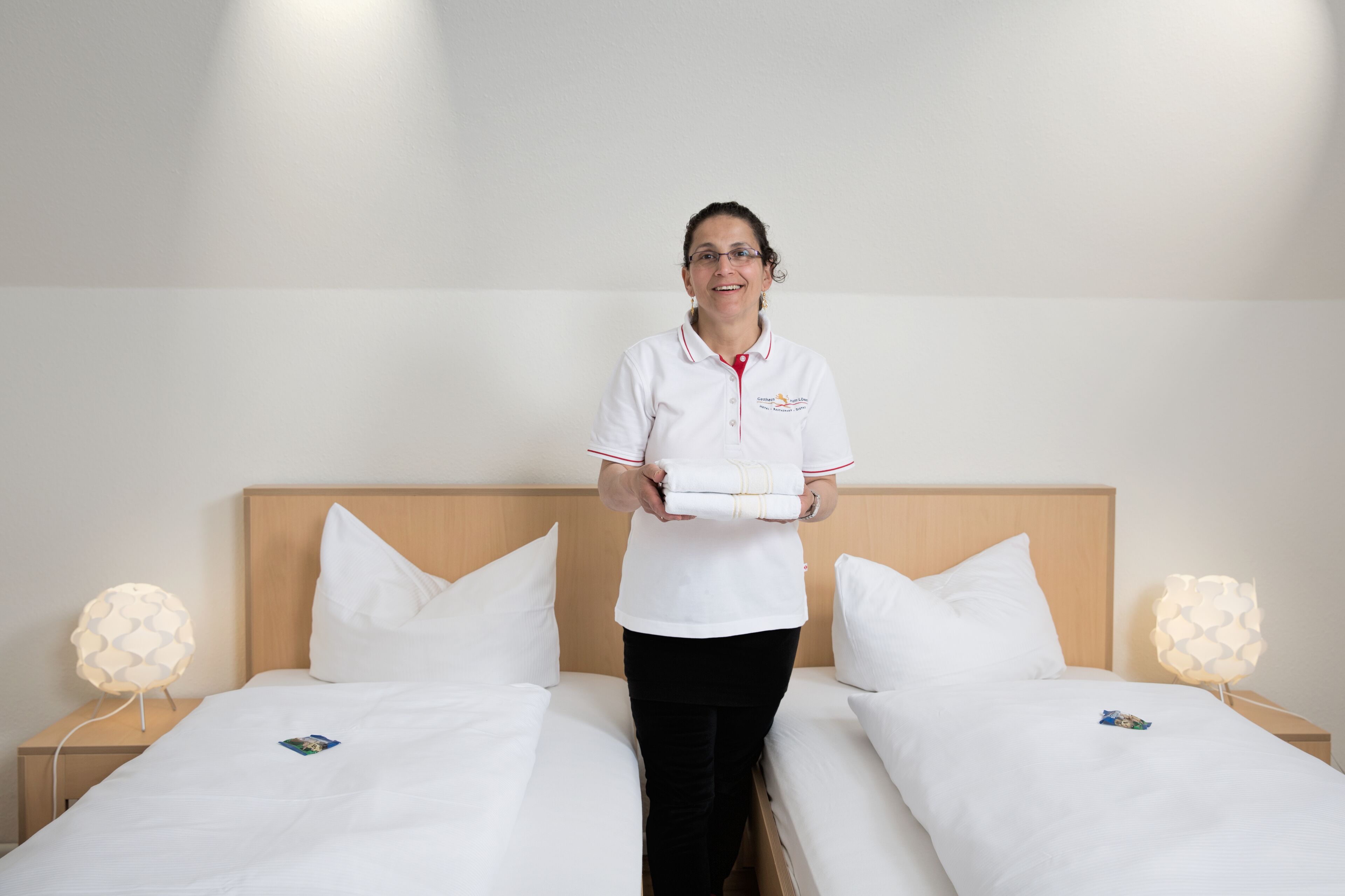 Ein Hotelzimmer mit zwei Betten, einem Holz-Kopfteil und Nachttischlampen.