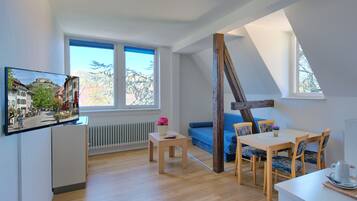 Un appartamento moderno con una zona mansardata, ampie finestre, un'area pranzo e una TV a parete.