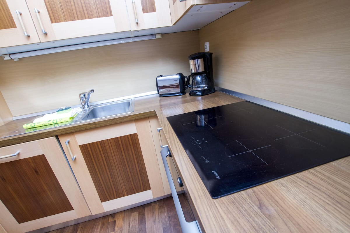Une cuisine compacte avec des meubles en bois, un évier, un grille-pain et une plaque de cuisson à induction noire.