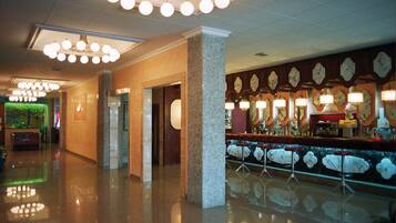 Un vestíbulo de hotel con zona de bar, piscina y mostrador de recepción.