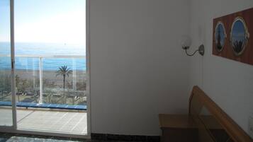 Una habitación con un amplio ventanal corredizo que da a un balcón con vistas al mar.