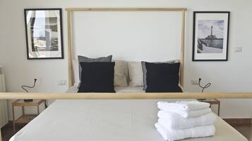 A neatly made bed with a wooden headboard, two bedside tables with lamps, and two framed pictures on the wall.