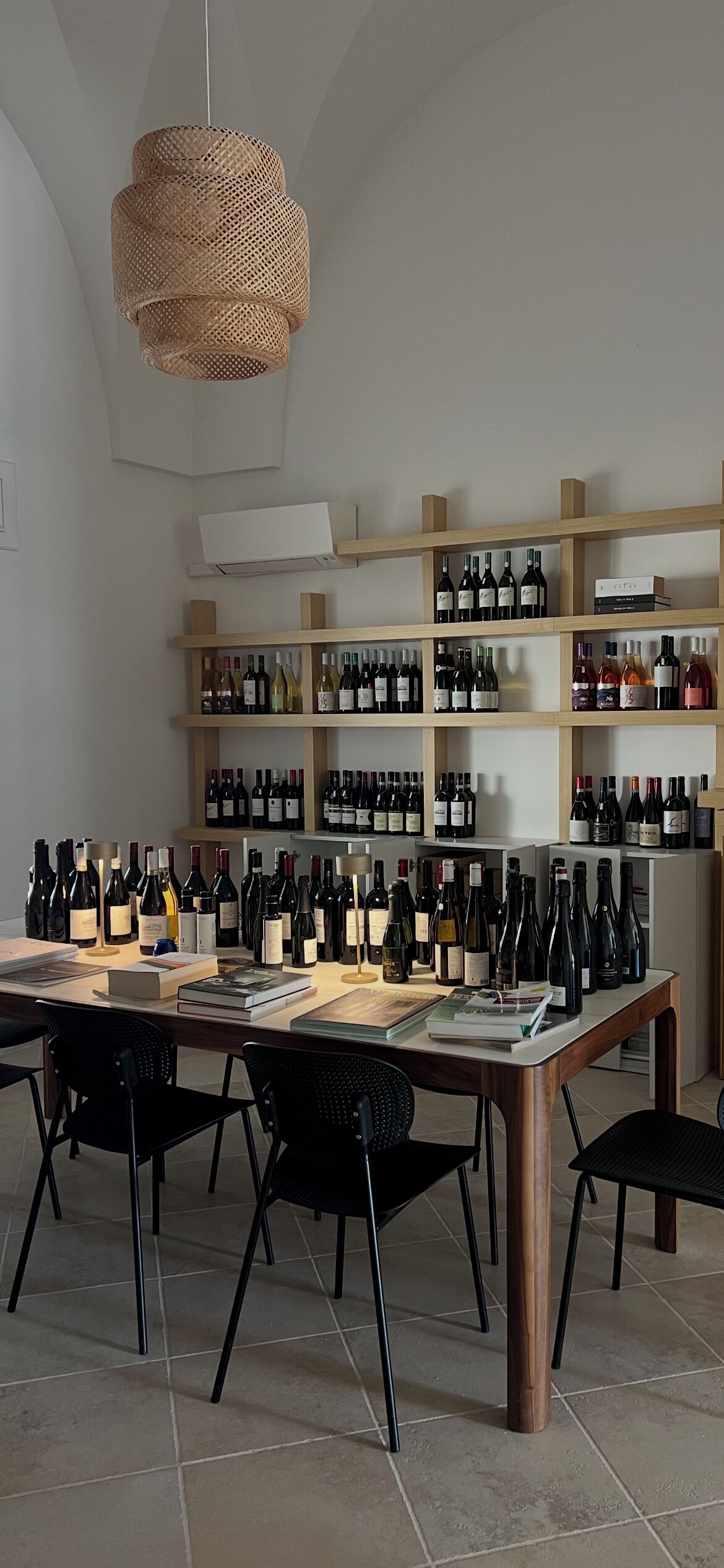A wine tasting room with a long table, black chairs, and shelves of wine bottles.
