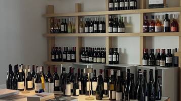 A wine tasting room with a long table, black chairs, and shelves of wine bottles.