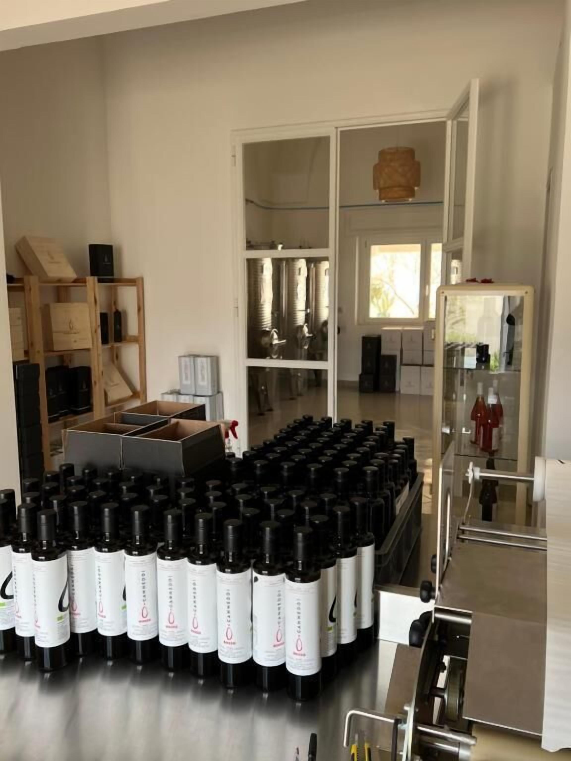 A kitchen area with stainless steel appliances, a wooden shelving unit, and a large number of black and white bottles.