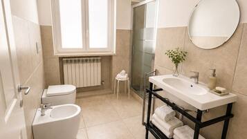 Un baño moderno con inodoro, bidé, lavabo y cabina de ducha de vidrio.