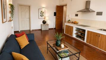 Uma sala de estar com sofá, mesa de centro e uma cozinha com armários e fogão.