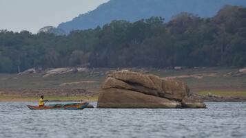 A person in a boat on a calm body of water with a large rock formation in the background.