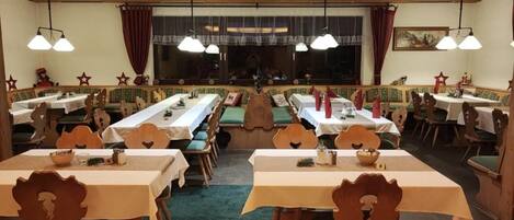 A restaurant with multiple tables and booths, wooden chairs, and a central bench area.